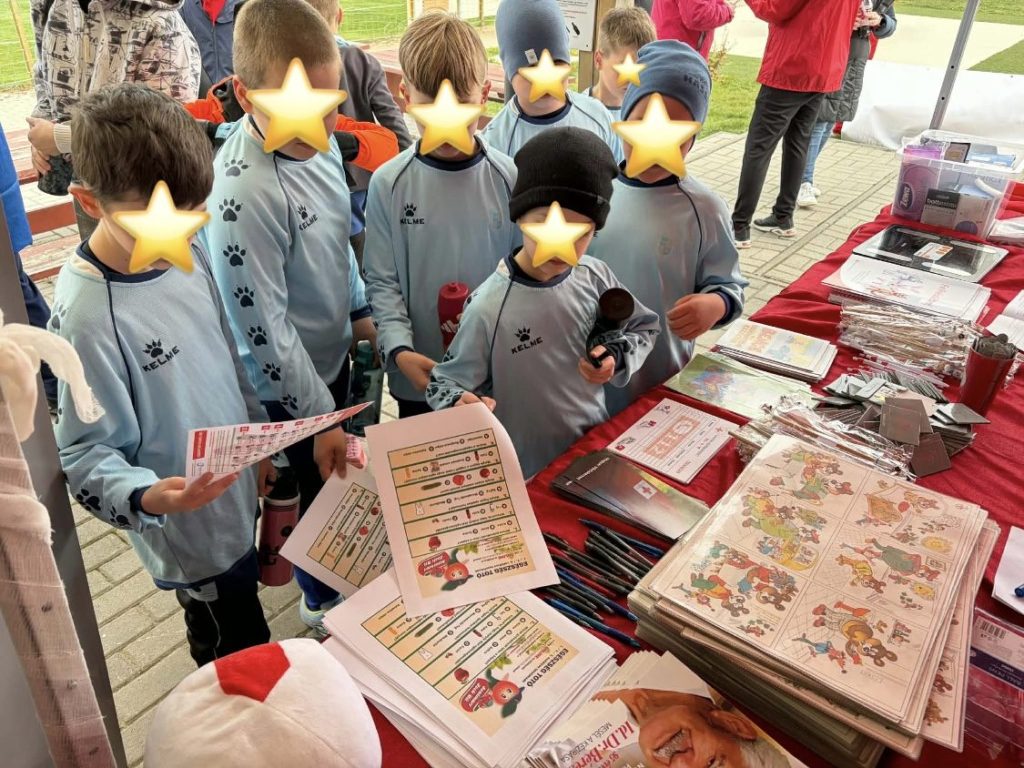 Focimezes gyerekek a Vöröskereszt információs asztalánál egészségügyi totót és kiadványokat nézegetnek